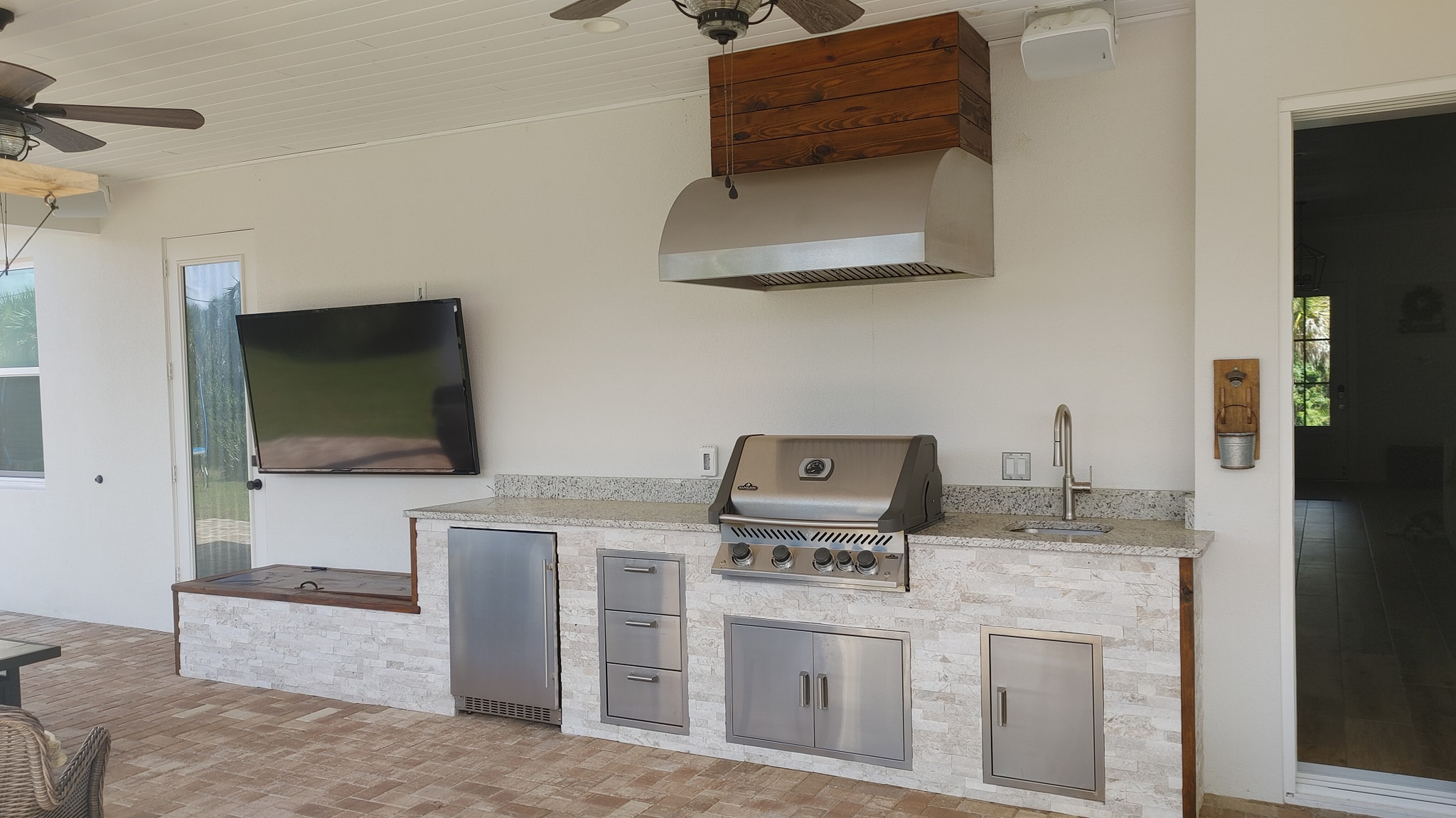 Room under construction with white brick fireplace, wooden mantle, chandelier, exposed wires, and debris on floor.